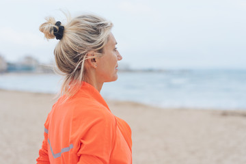 ältere frau im sport-outfit schaut über das meer