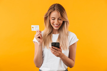 Portrait of a happy young blonde girl showing plastic credit