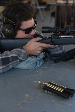 Man aiming sniper rifle at target in shooting range