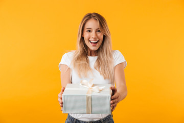 Portrait of a cheerful young blonde girl giving present box