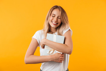 Portrait of a satisfied young blonde girl hugging present
