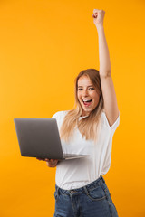 Portrait of a joyful young blonde girl holding laptop