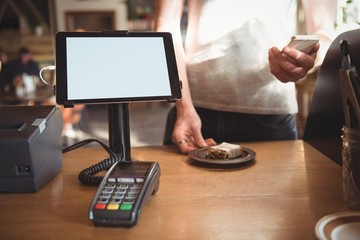 Mid section of waiter using mobile phone while serving breakfast