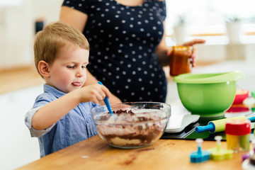 Smart cute child helping mother in kitchen