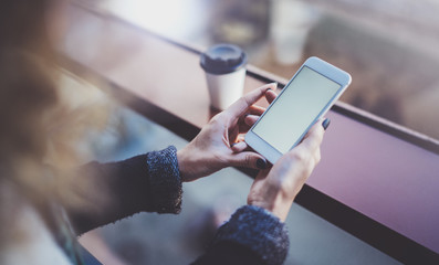 Woman holding hands smartphone and texting message.Female hands using mobile phone.Closeup on blurred background.Flares, bokeh effects. Mock-up.