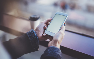 Woman holding hands smartphone and texting message.Female hands using mobile phone.Closeup on blurred background.Flares, bokeh effects. Mock-up.