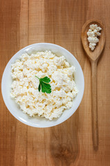 Fresh cottage cheese in a white bowl with spoon