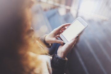 Woman holding hands smartphone and texting message.Female hands using mobile phone.Closeup on blurred background.Flares, bokeh effects. Mock-up.