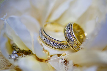 Naklejka premium Wedding rings made of metal lie on a beautiful bouquet of fresh flowers. The concept of holidays and ceremonies.