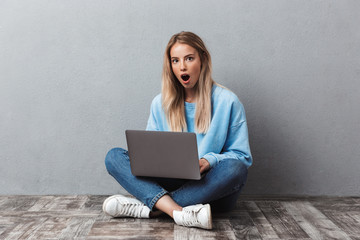 Shocked young blonde girl using laptop computer