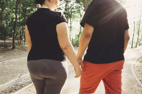 Overweight Couple Walking Together In Park. Weight Losing, Outdoor Activities, Healthy Lifestyle Concept. 