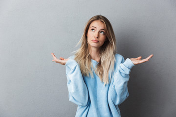 Portrait of a confused young blonde girl - obrazy, fototapety, plakaty