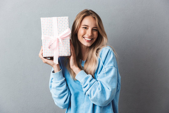 Portrait of a smiling young blonde girl holding present box