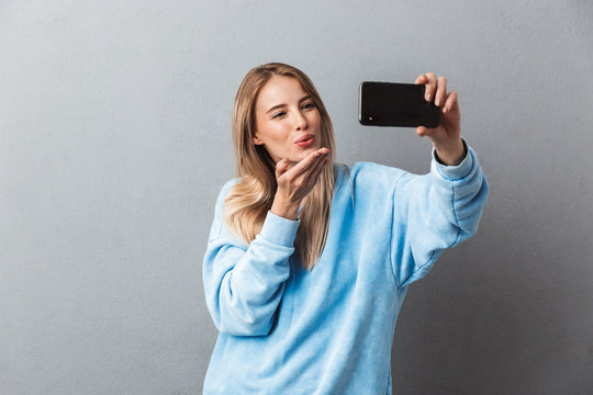 Smiling young blonde girl taking a selfie