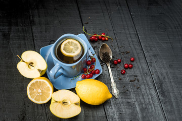 A cup of tea with lemon on black background