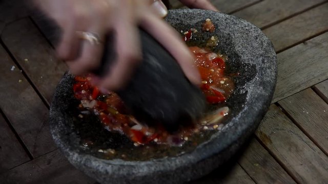 video footage hand grilling chilli using ulekan traditional utensil from stone