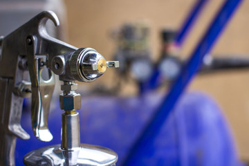 spray gun in hand on the blurred background of the compressor