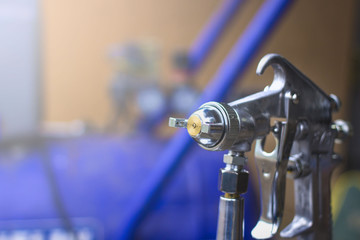 spray gun in hand on the blurred background of the compressor