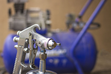 spray gun in hand on the blurred background of the compressor