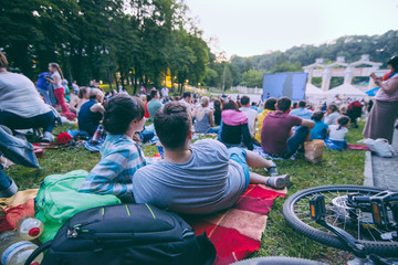 people watching movie in open air cinema in city park