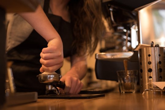Mid section of barista preparing coffee