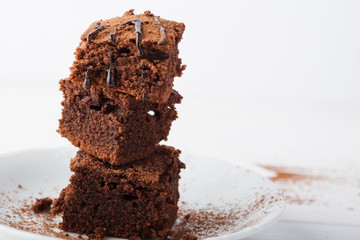 Stack of brownies on white wooden background. Chocolate cake close up. Copy space. 