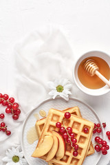 Flat lay of traditional belgian waffles with fresh fruit, nectarine, currant and honey on white background. Breakfast. Top view with copy space.
