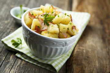 Homemade warm potato salad with onion and fried bacon