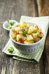 Homemade warm potato salad with onion and fried bacon