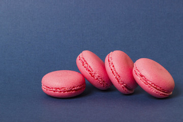 Obraz na płótnie Canvas Pink macaroons on a blue background, closeup, copy space