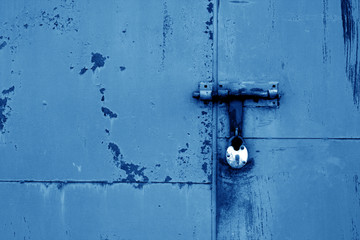 Old padlock on metal gate in navy blue color.