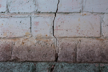 Crack on an old multi-colored brick wall