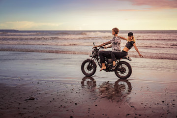 Fototapeta na wymiar young couple riding motorcycle on ocean beach