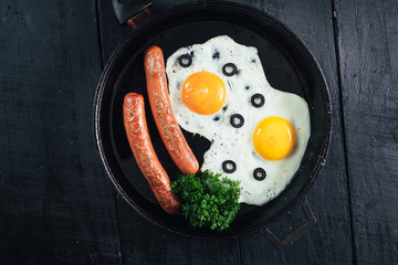 scrambled egg with sausages in the pan and tomatoe juice on black background. Copy space