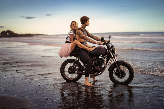 side view of couple hugging on motorcycle on ocean beach © LIGHTFIELD STUDIOS