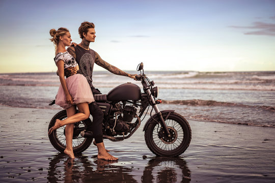 boyfriend hugging girlfriend and sitting on motorcycle on ocean beach