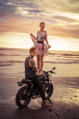 happy girlfriend standing on motorcycle near boyfriend on ocean beach