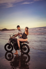 Fototapeta premium side view of couple riding motorcycle on seashore