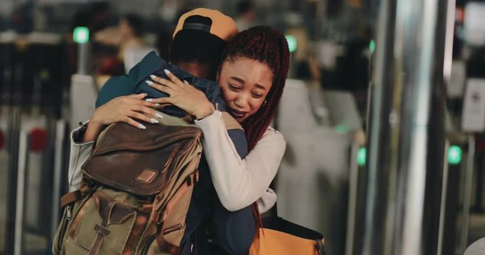 Young couple embracing and crying during emotional farewell at airport