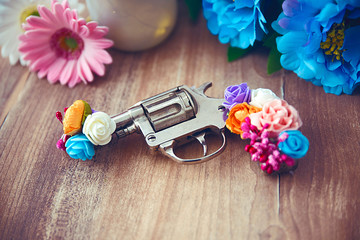 Gun decorated with flowers on wooden table