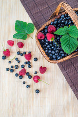 A basket with blueberries and raspberries on wooden background