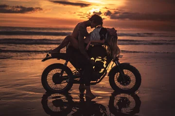Foto op Plexiglas sexy couple hugging on motorbike at beach during sunset © LIGHTFIELD STUDIOS