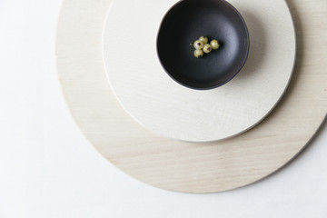 A composition of ceramics, white currants and wooden plates on a white surface.