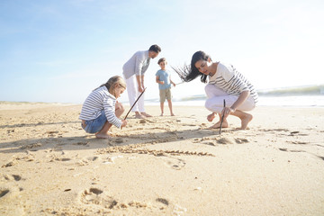 Fototapeta premium Family having fun writing messages on sandy beach