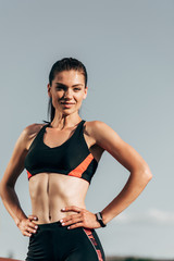 Fototapeta na wymiar beautiful athletic woman in sports bra posing against blue sky