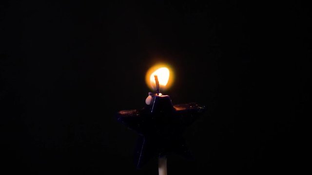 Candle burning in a dark room.
