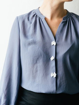 Portrait of a woman in a lavender blue shirt with white wild flowers as buttons.