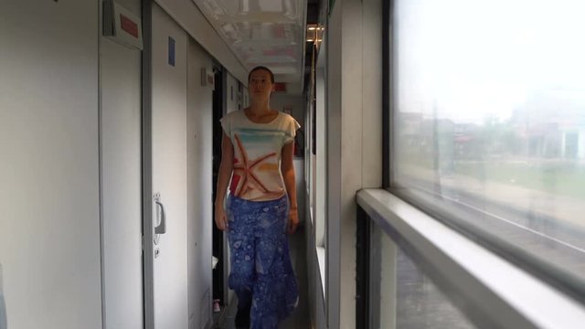 A woman walks by the train car and enters the compartment