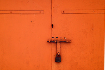 Orange color old padlock on metal gate.