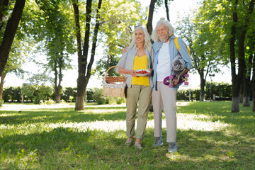 Close to nature. Joyful elderly people being in the park while organizing a picnic